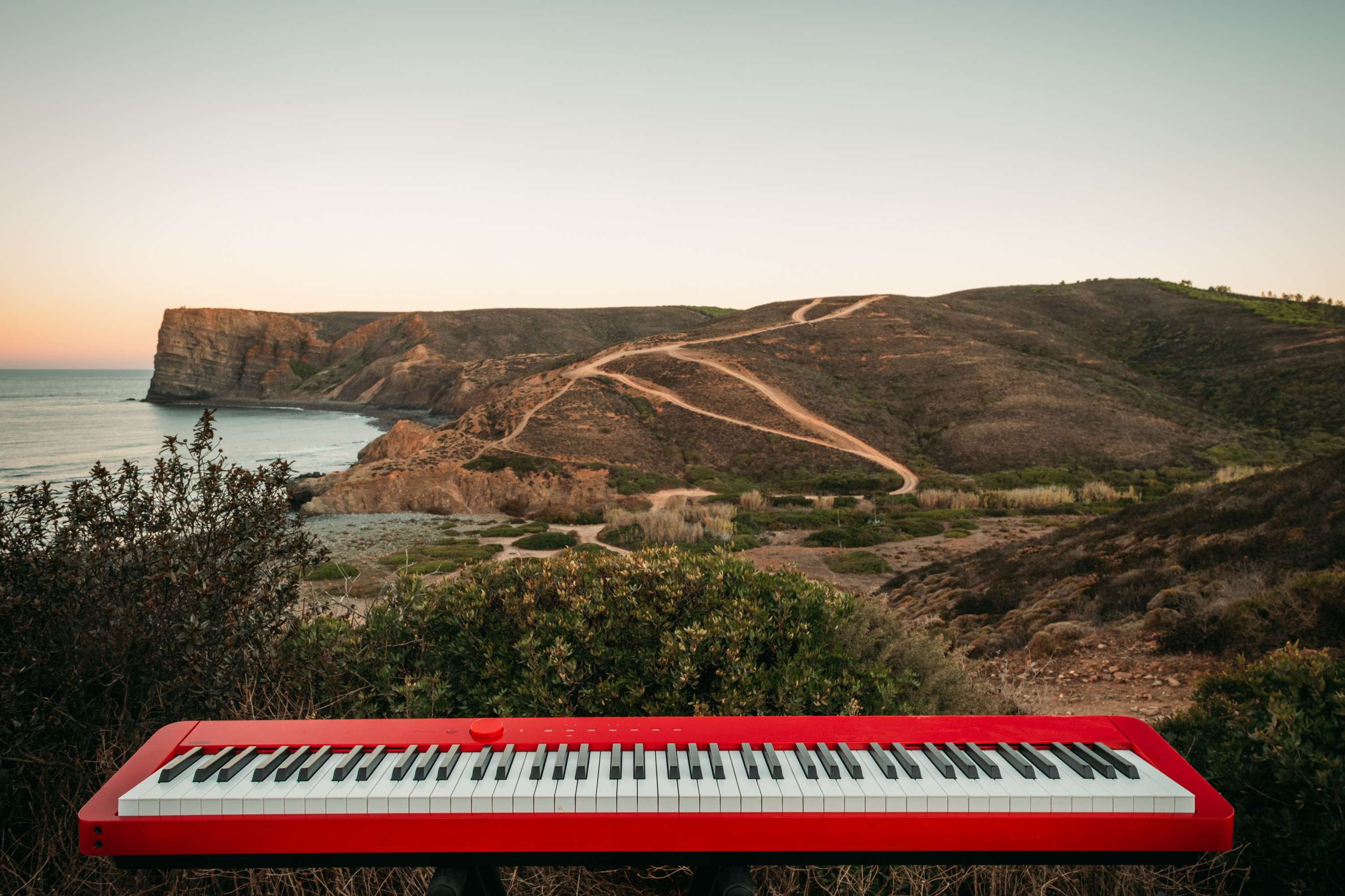 Rotes Klavier vor einer Küstenlandschaft in Portugal – Klavier lernen darf sich anfühlen wie Abenteuer